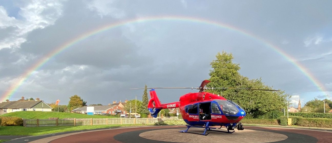 A Devon Air Ambulance helicopter underneath a rainbow