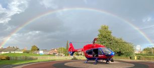 A Devon Air Ambulance helicopter underneath a rainbow