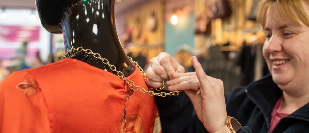 Retail volunteer dressing a mannequin