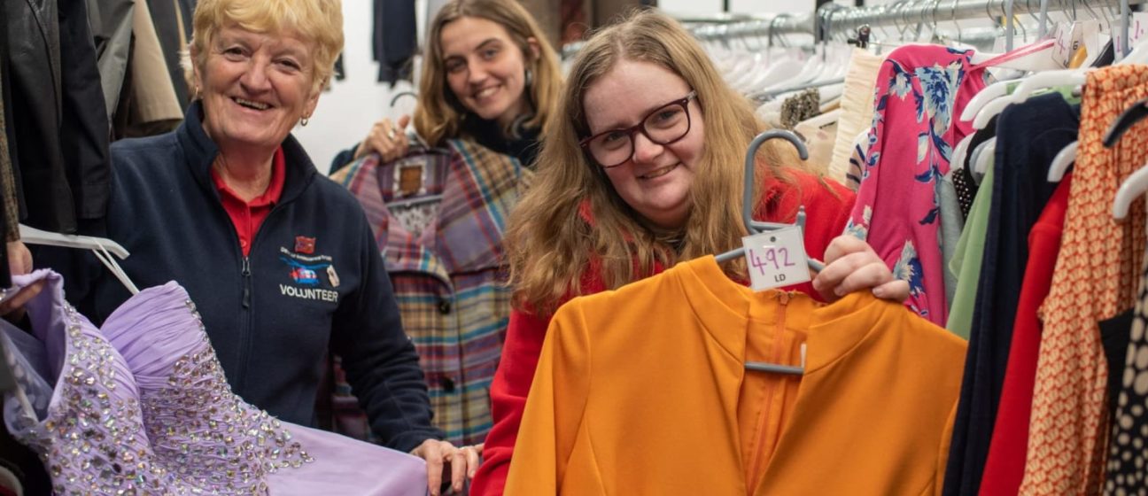 Three retail volunteers showing preloved garments