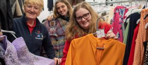 Three retail volunteers showing preloved garments