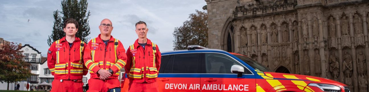 Three crew members with our critical care car by Exeter Cathedral